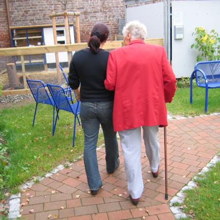 Photo d'une personne munie d'une canne accompagnée par un aidant