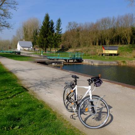 Vue le chemin de halage à Lamotte Brebières. Un vélo est stationné sur le chemin.